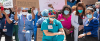 Nurses kneeling with signs.